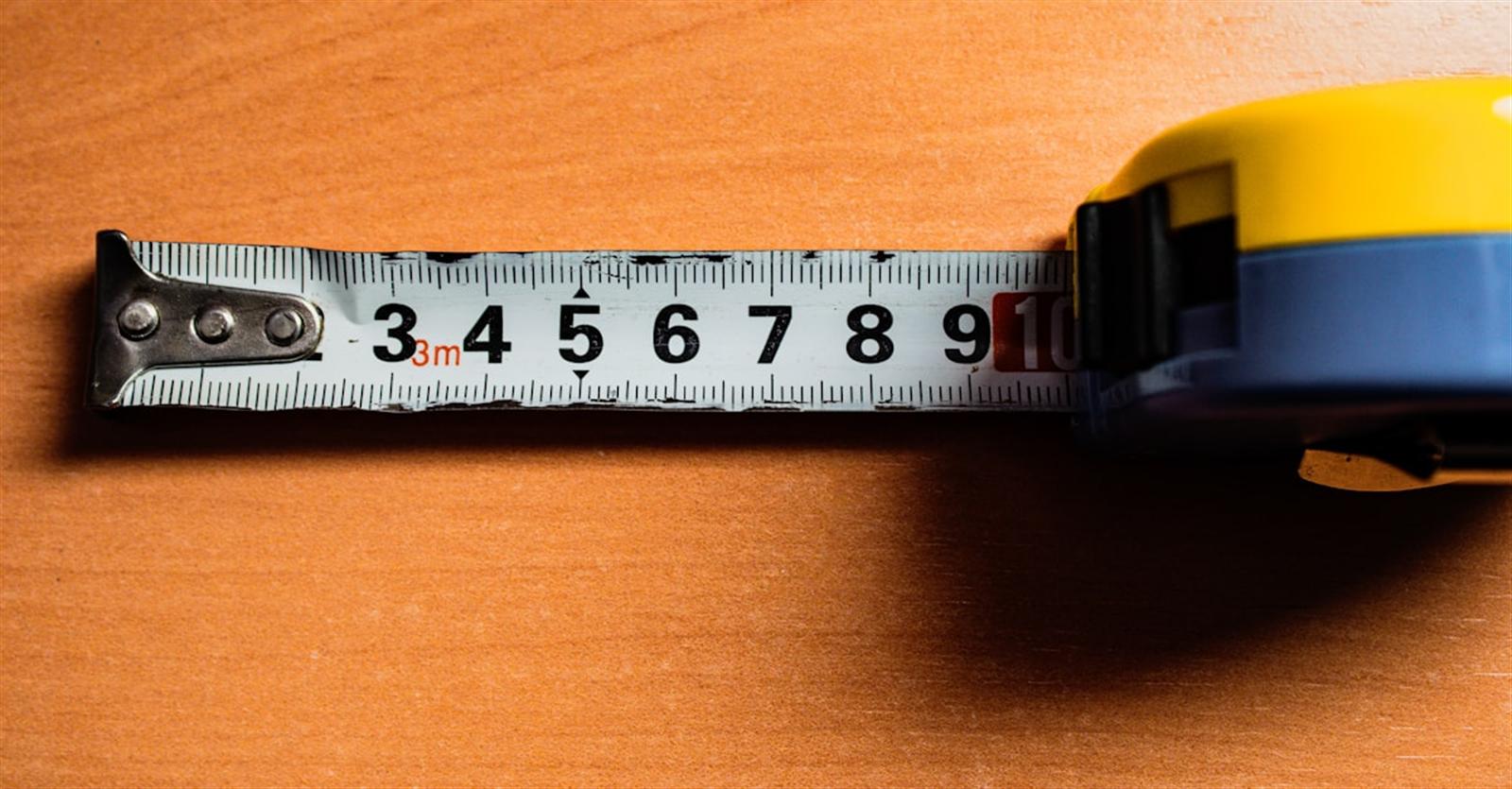 Tape measure with markings on a wooden surface for measuring cabinet dimensions
