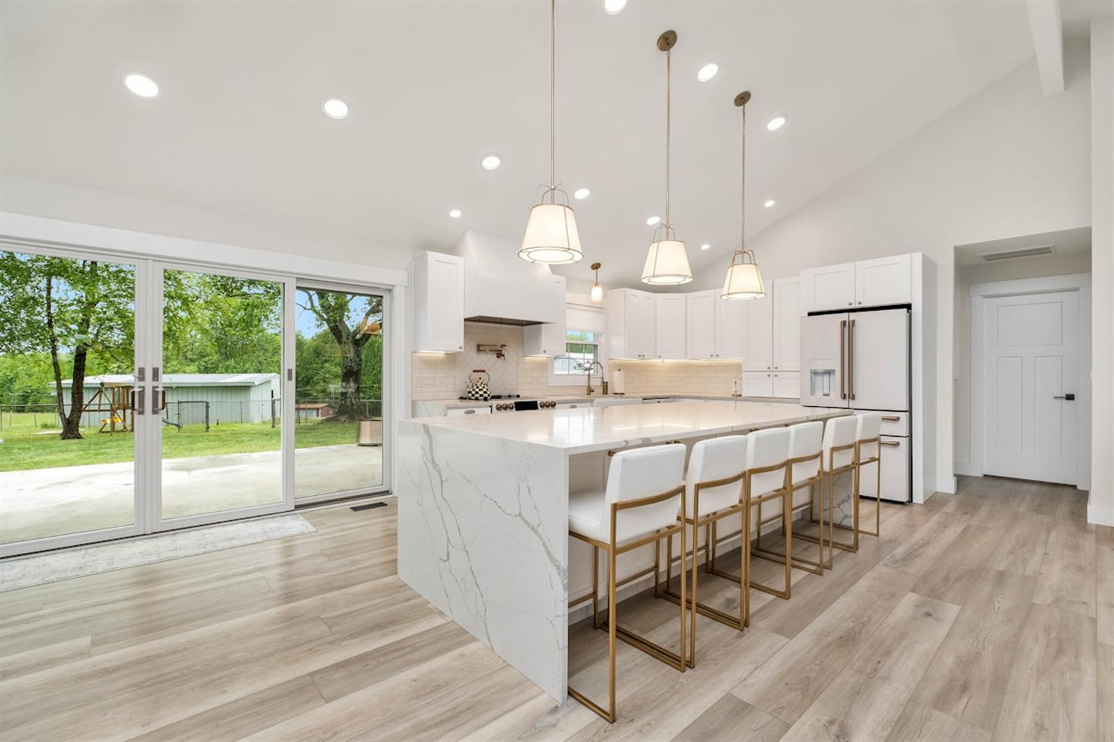Large kitchen island with polished marble countertop and pendant lighting